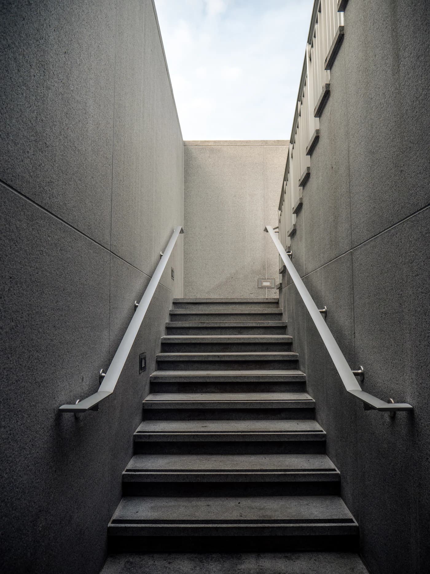 A concrete staircase leading upward toward daylight.