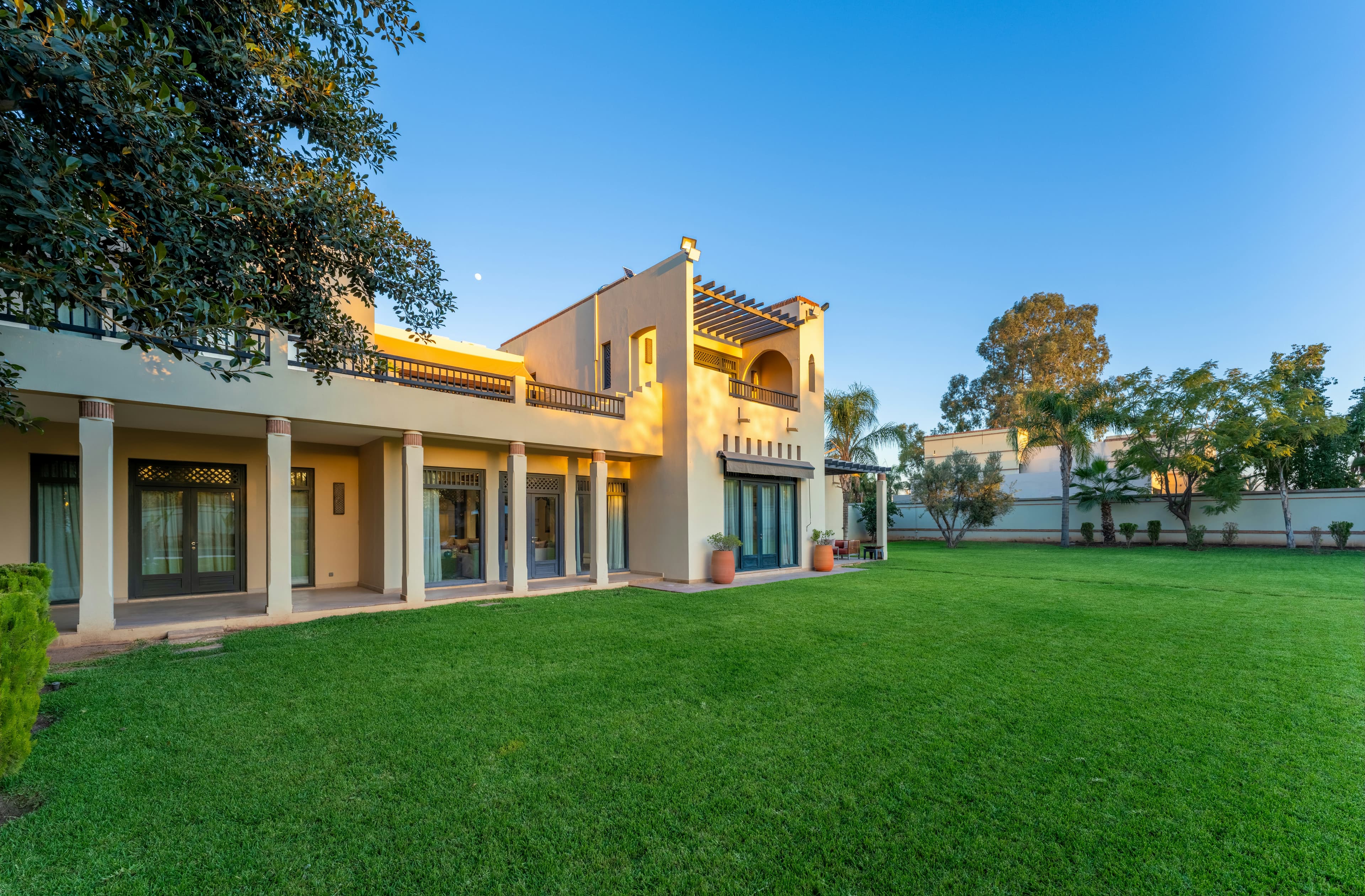 A two-storey residential house with a wide lawn in late-afternoon light.