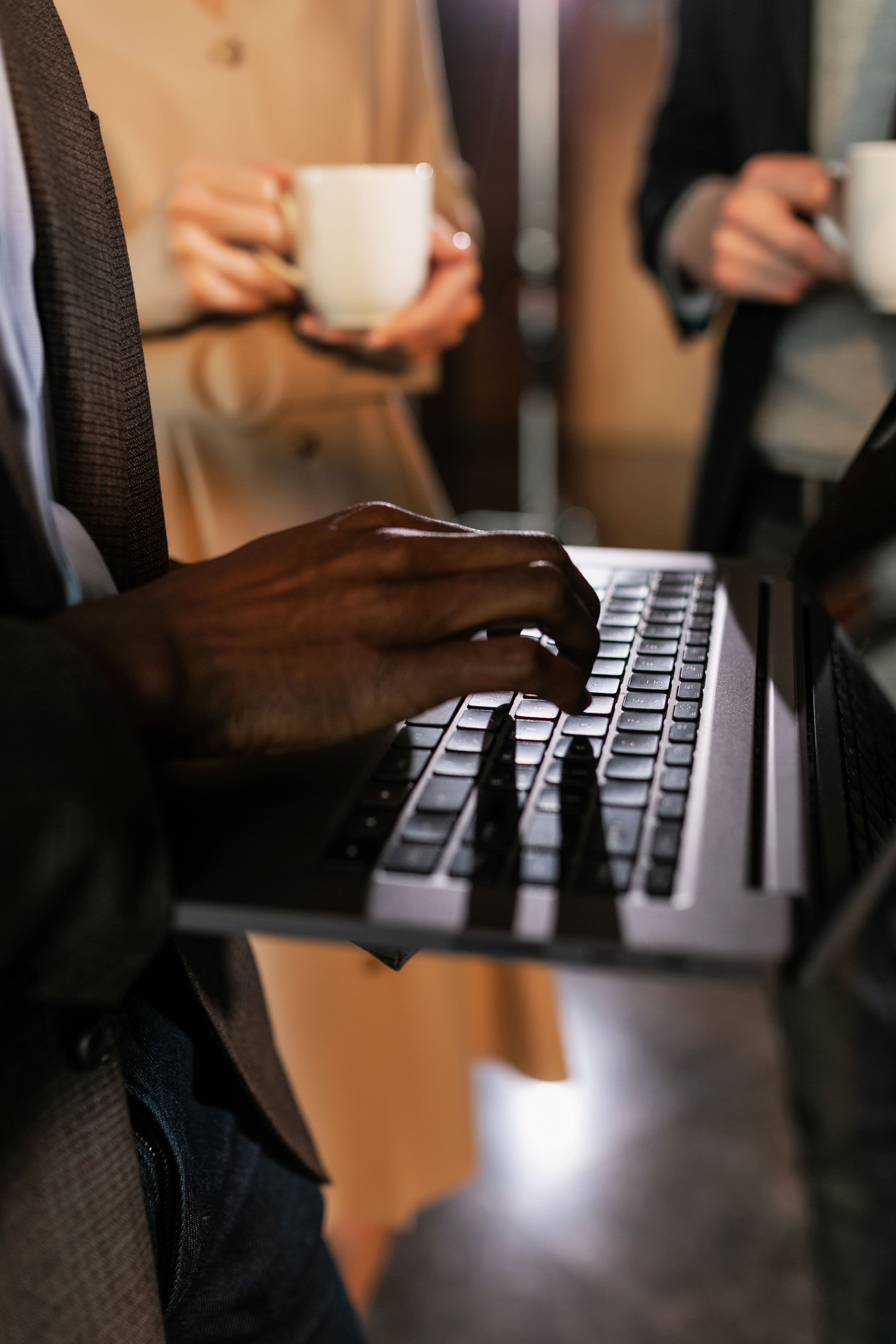 Close-up of hands typing on a laptop keyboard in low light.