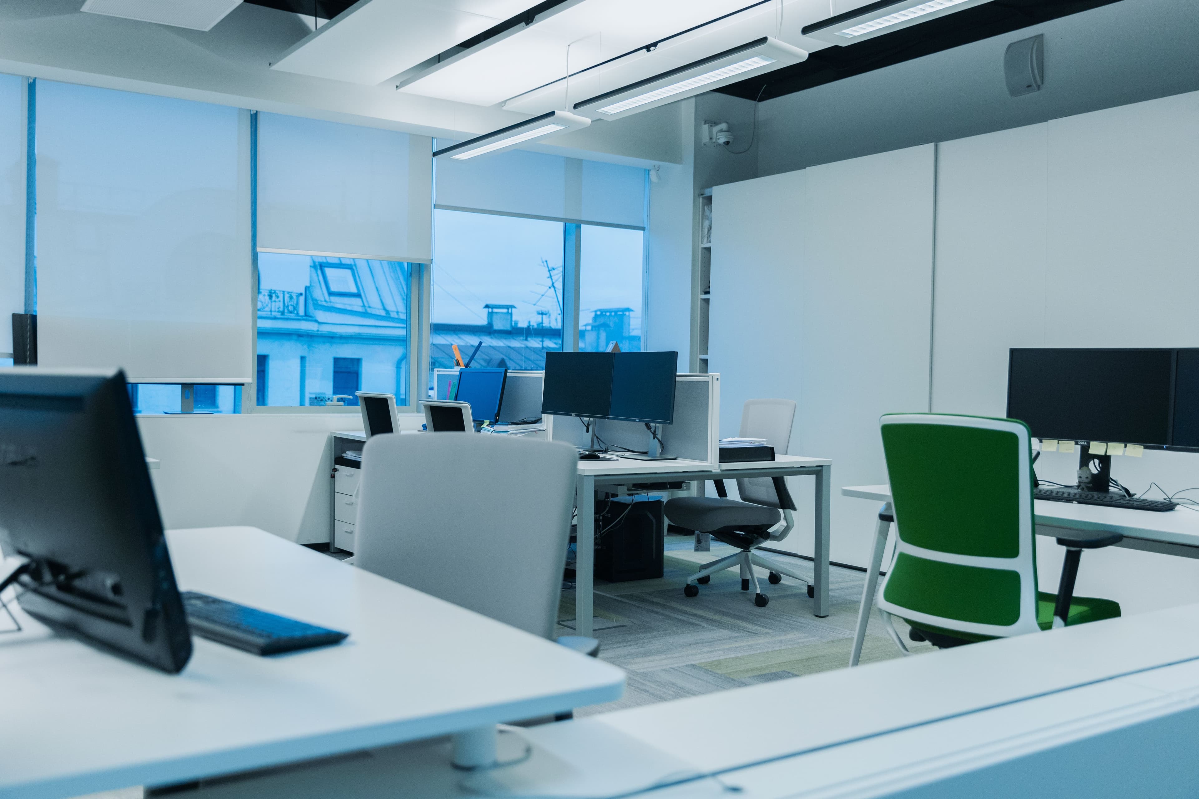 A quiet, light-filled office with desks and monitors behind a glass wall.